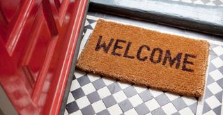 a coir welcome doormat by a red front door