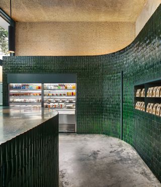 The green-tiled Niddo Café in Mexico City’s Juárez neighbourhood. A cafe with a rounded counter, wall fridges and a green tiled curved wall.