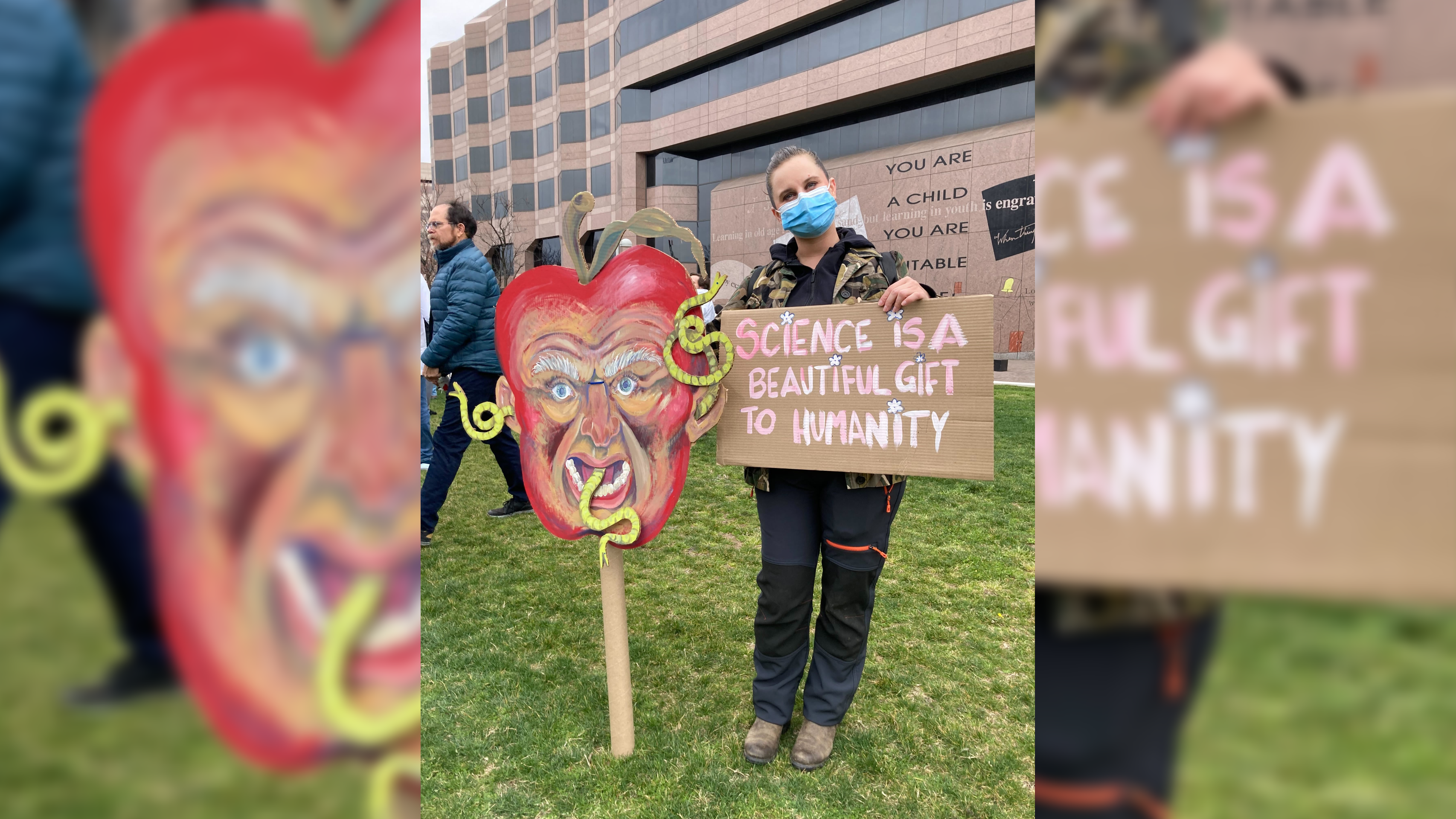 Fotografii de afișe și protestatari la mitingul Stand Up for Science din Raleigh; O femeie stă cu două afișe, dintre care unul este un cap enorm RFK Jr. ca un măr putred cu viermi