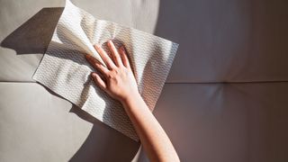 woman cleaning leather sofa with white wipe