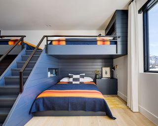 kids bedroom with bunkbeds painted dark blue, double bed underneath and wood floors