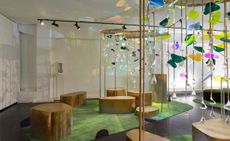 A lounge space consists of brass seating modules, with Plexiglas structures in different shapes and colours falling down from the ceiling.