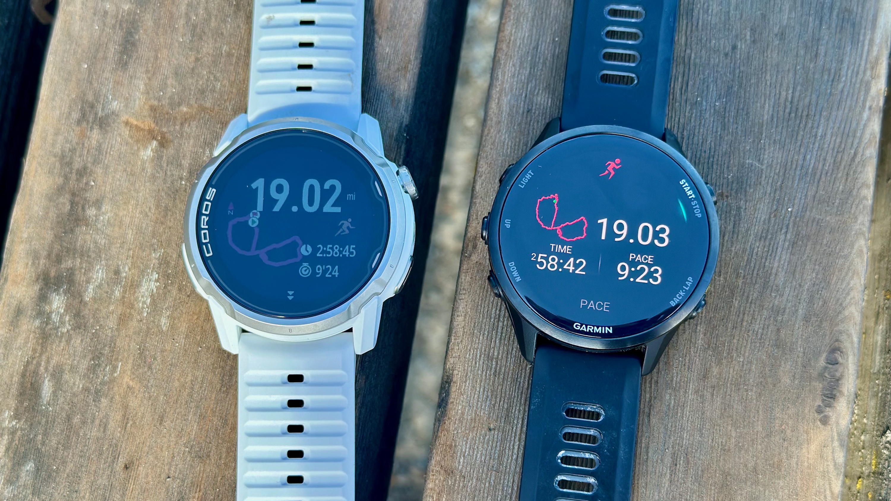 The COROS APEX 4 (left) and Garmin Forerunner 970 (right) sitting on a wooden bench, showing near-identical post-workout totals for a 19-mile run.