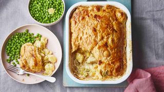 Cheese and leek potato pie in a rectangular tin served with green vegetables.