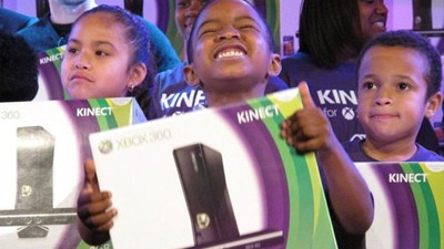 Boy holds Xbox 360 with Kinect and smiles