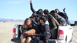 Seven students pose next to the rocket in the back of a pick-up truck