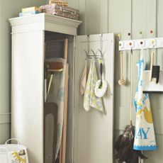 Cream cupboard with the door open, revealing all of the cleaning products and supplies inside