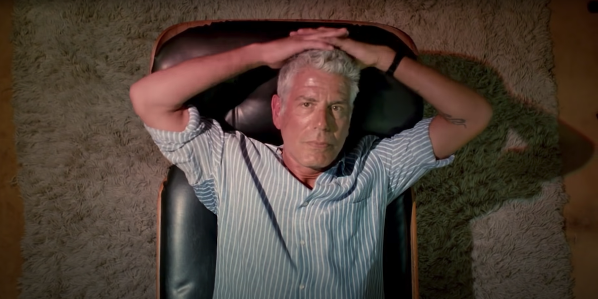 Anthony Bourdain lays down and stares into the camera in a scene from &#039;Roadrunner&#039;