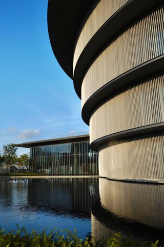 A closer look at the exterior of the He Art Museum. The circular building, surrounded by water.