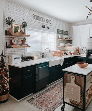Mono farmhouse kitchen with central butcher's block on wheels, patterned runner on floor, wood floating shelves, and metro tiles covering full wall.