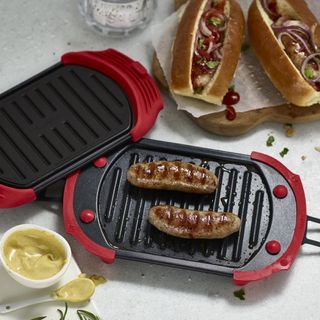 microwave grill with red handles and hot dogs