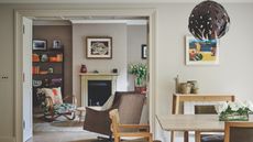 Stud wall between living room and dining room showing taupe walls and moulding around door frame and ceiling with a mid century modern twist on colorful furnishings and shelving