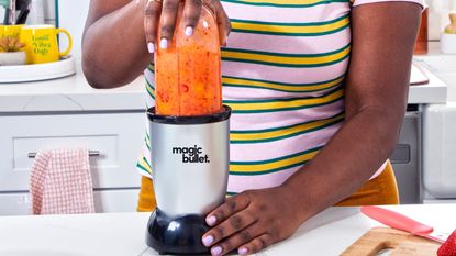Magic Bullet Blender on a countertop with an orange smoothie inside