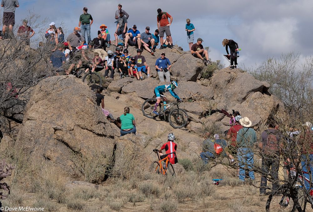 Spectators watch racers descend one of the technical sections of the course