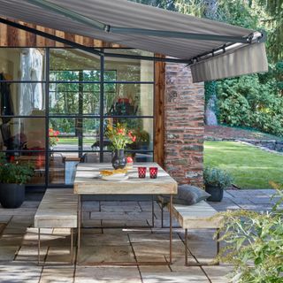 outdoor dining with Thomas Sanderson awning, garden room to rear, lawn, plants