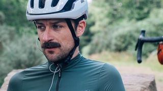 A white man with a moustache wears the sage green le col pro jersey II
