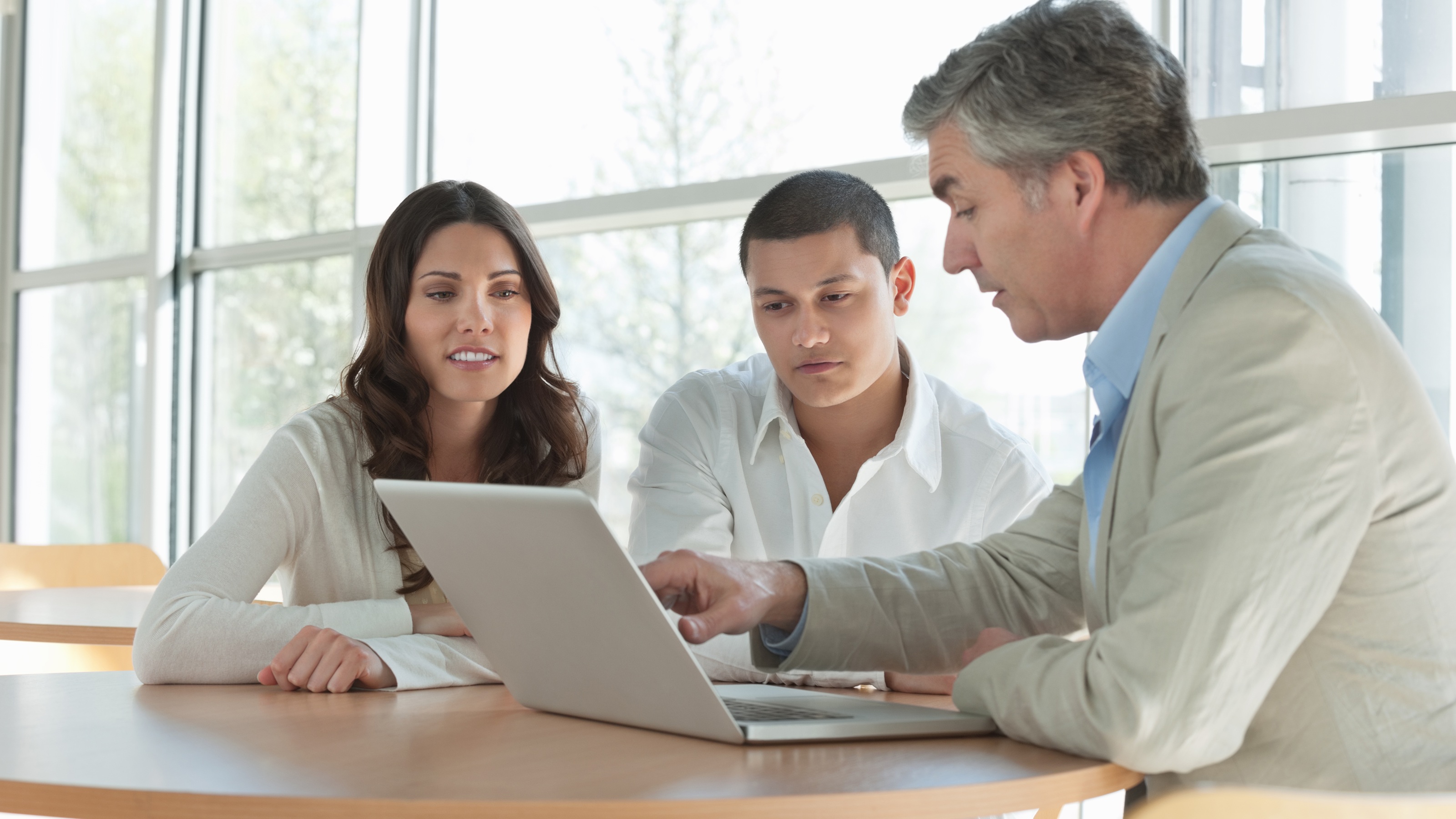A financial adviser goes over a young couple&#039;s finances in an office.