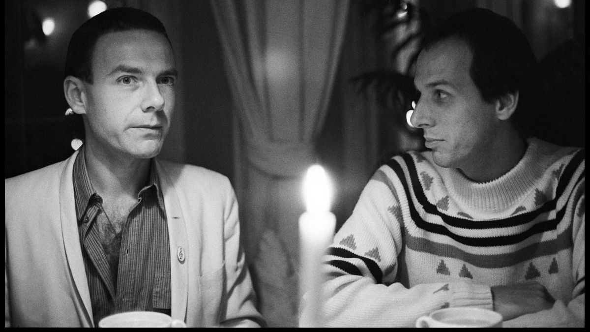 black and white candid shot of King Crimson&#039;s Robert Fripp and Adrian Belew by candlelight at the Portobello Hotel, London in 1981 