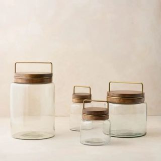 A brass and wooden set of Magnolia glass food cannisters