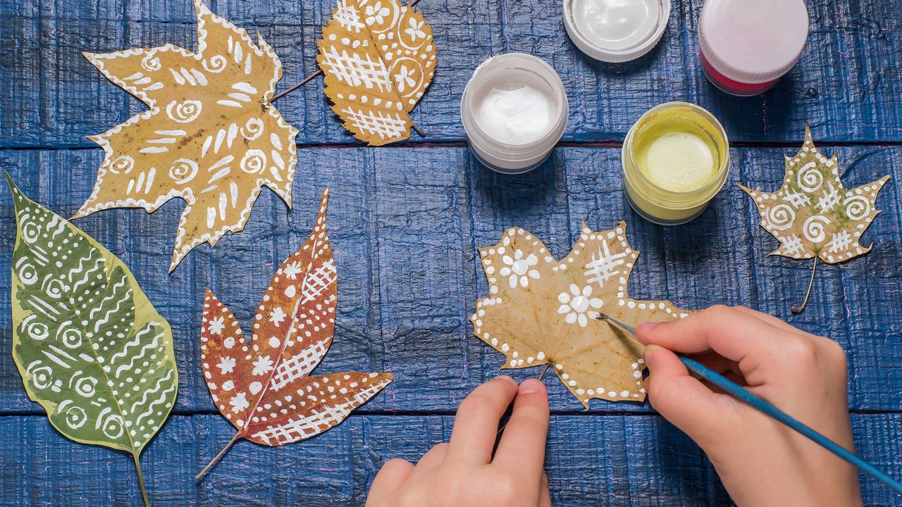 Hands painting patterns on dried autumn leaves