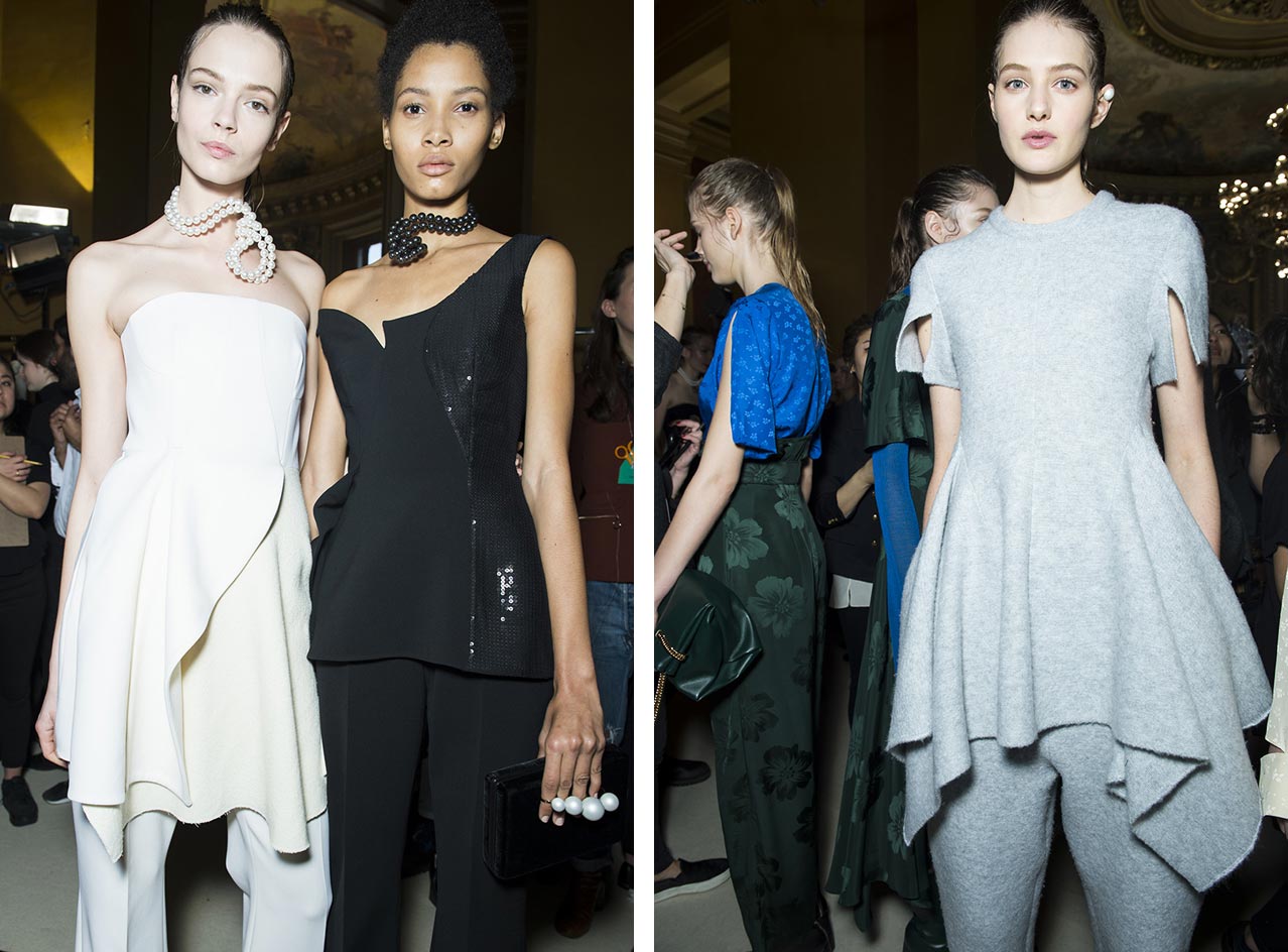 Models wearing trouser suits with long capes in cream, black and light grey