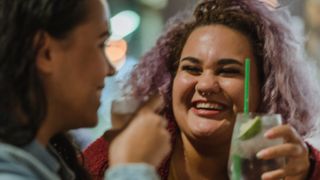 Laughing young women having drinks at a bar - stock photo