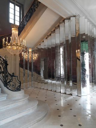 A grand staircase with a chandelier and a mirrored screen