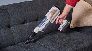 Shark Detect Pro cordless vacuum in handheld mode being used on a sofa