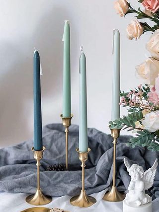 four green candles in gold candlesticks on a tabletop