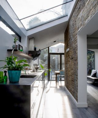 side return extension with skylights and kitchen units opposite original brick wall leading to dining area at end