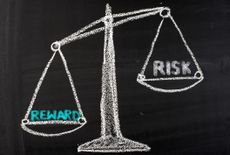 chalkboard drawing of a balancing scale with risk on one side and reward on the other