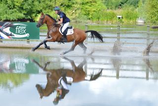 Image of a horse and rider cantering through water at a competition in the US