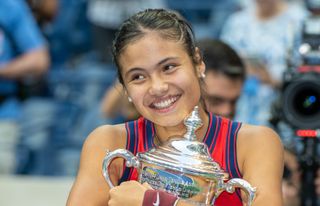 Tennis champion Emma Raducanu hugging her trophy after US Open victory