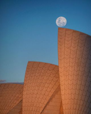 the full moon rises over the Sydney Opera House