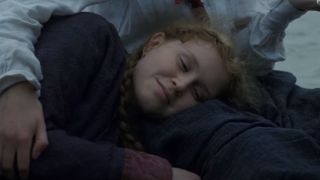 Eliza Scanlen as Beth March resting on her on her sister's lap smiling in Little Women