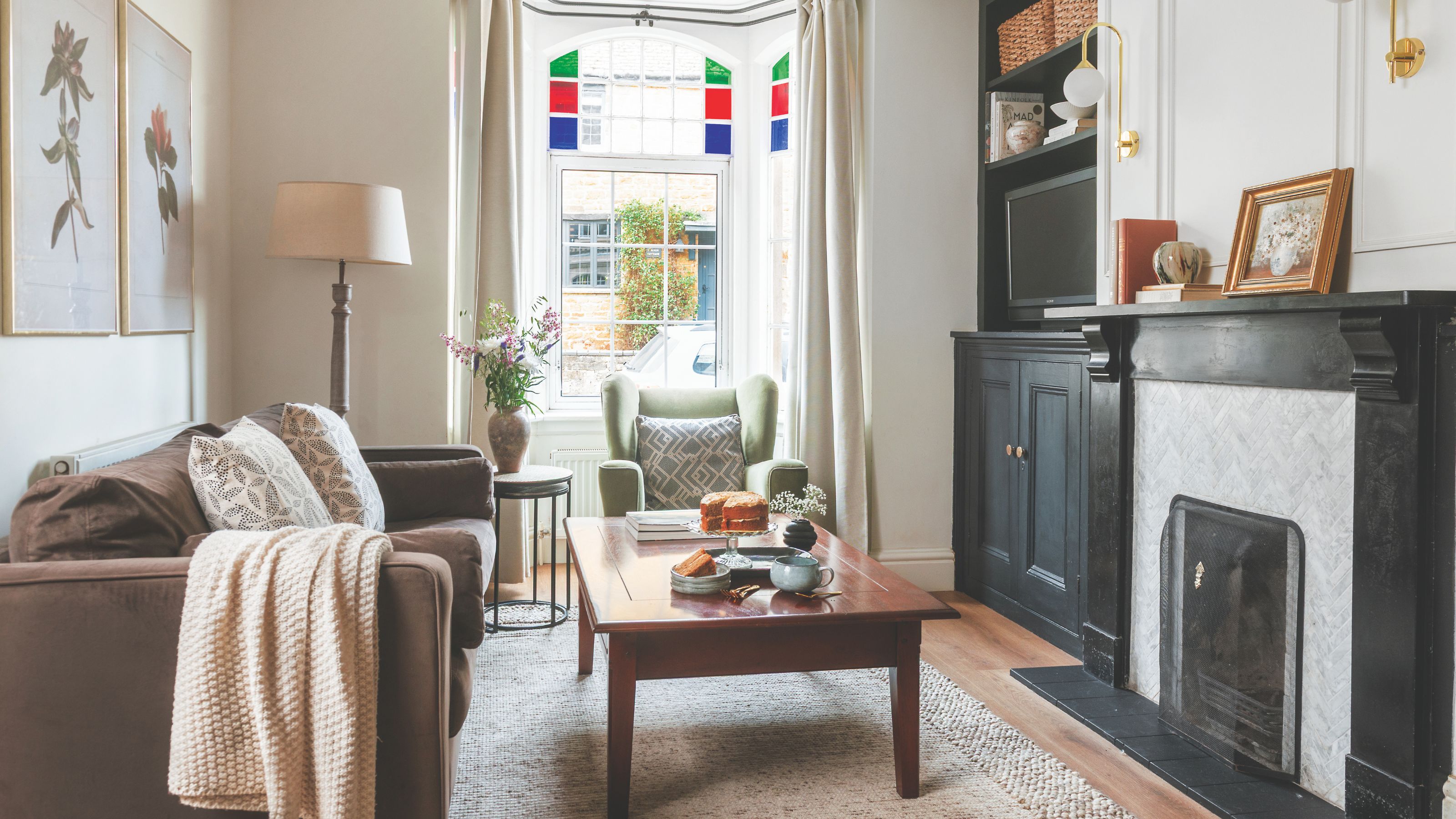 Small living room painted in neutral colours, with a black fireplace and fitted TV unit in the alcove