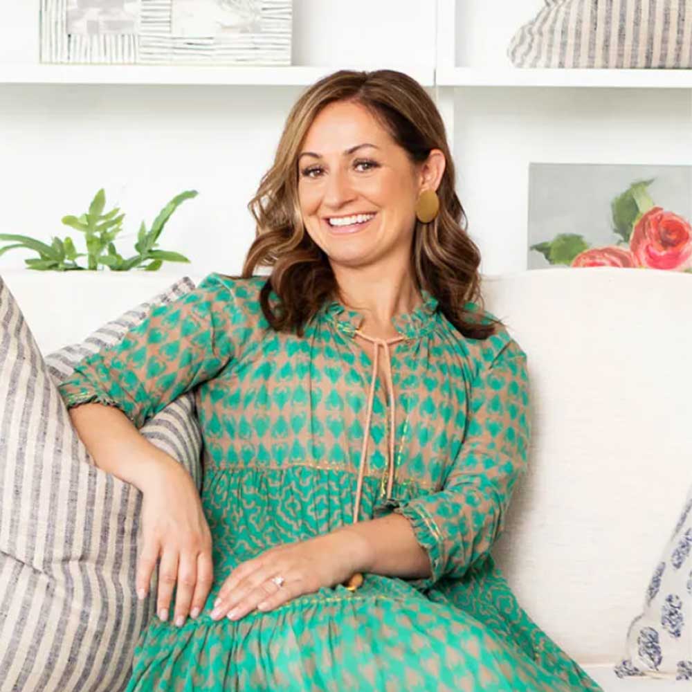 picture of interior designer Amy Peltier a woman wearing a green dress sitting on a sofa