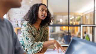 Woman sitting at a table at work delegating work to others