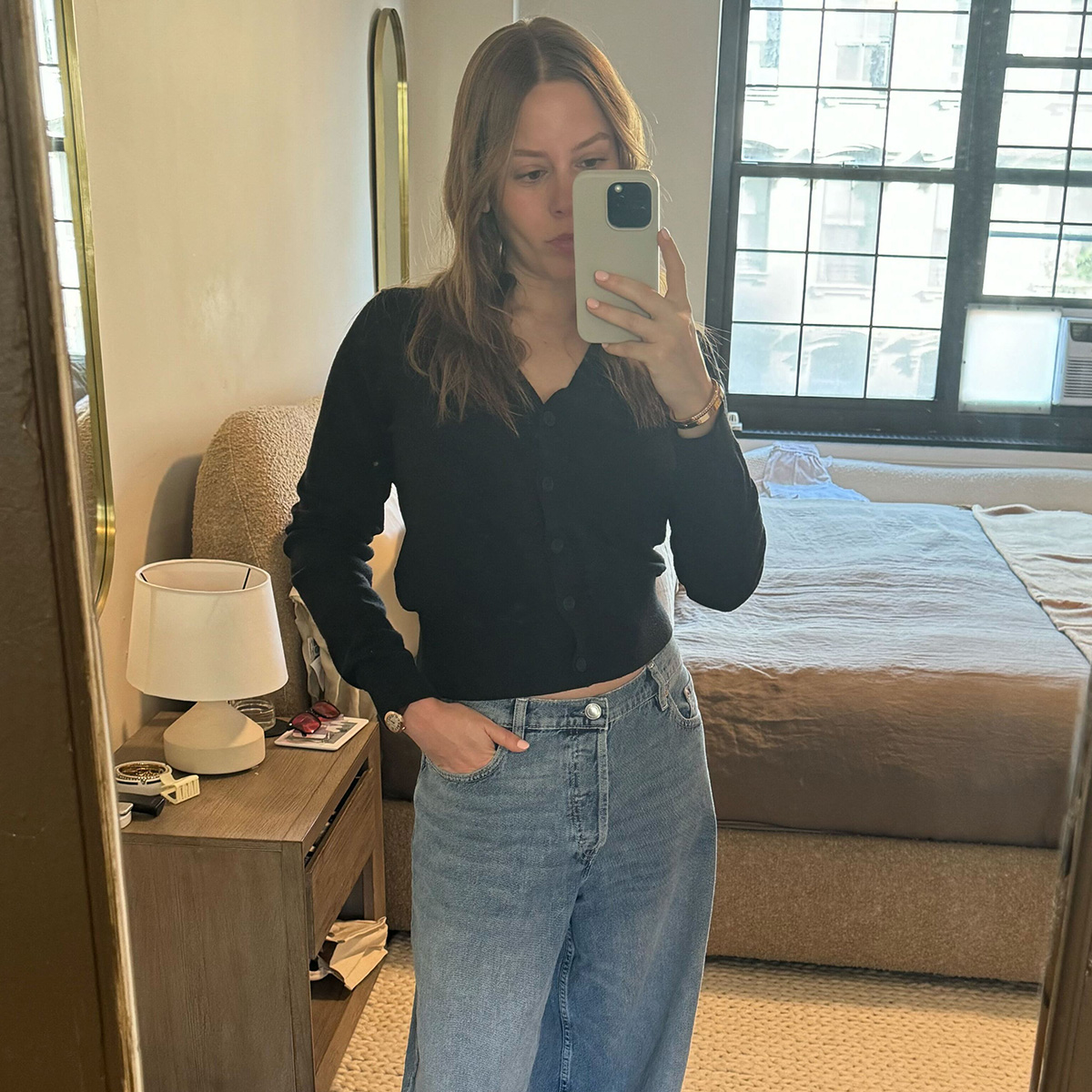 Nikki wears a black cardigan and DL1961 baggy jeans.