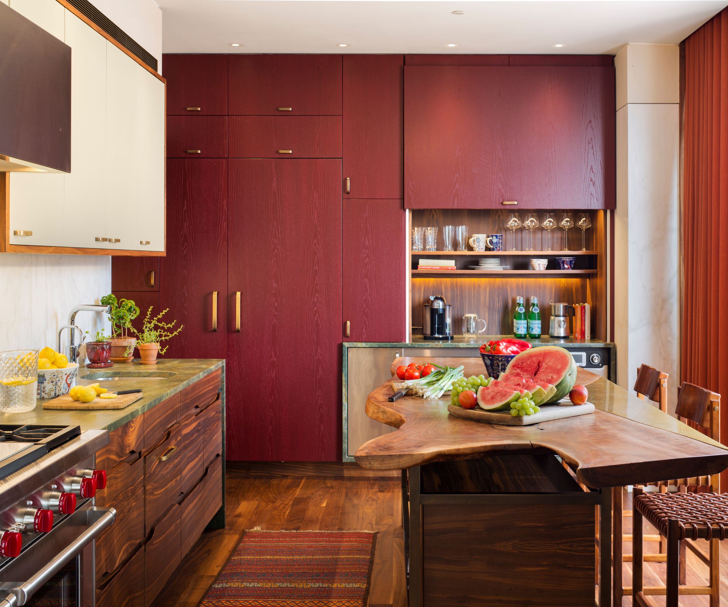A red and white kitchen with a wooden island and green leathered quartzite countertops