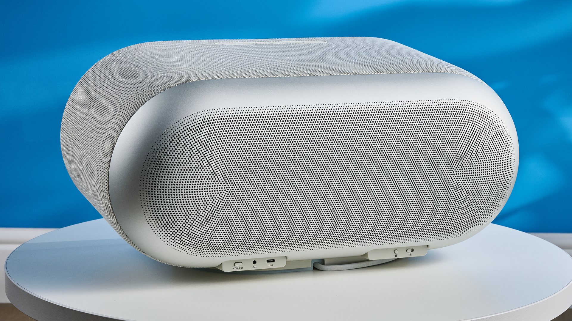 the denon home 600 home speaker in stone color photographed against the blue tom's guide background