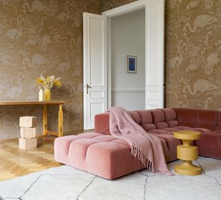 living room with beige patterned wallpaper, coral couch, cream rug