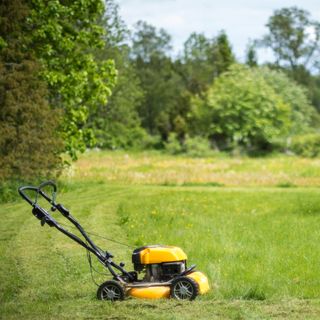 Yellow lawn mower next to a patch of grass