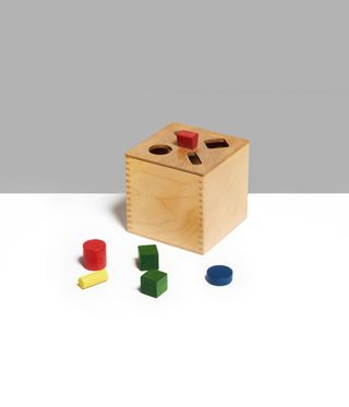 A wooden puzzle toy consists of a box with geometrical parts that fit into the openings on the box.