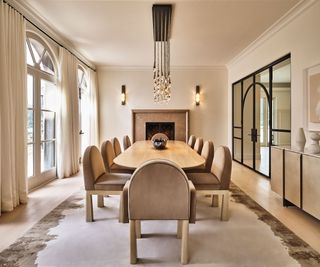 Large, modern dining room space in light beige with classic area rug, uoholstered dining table furniture, and more rich accents