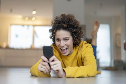 Woman lying on the floor at home using mobile phone