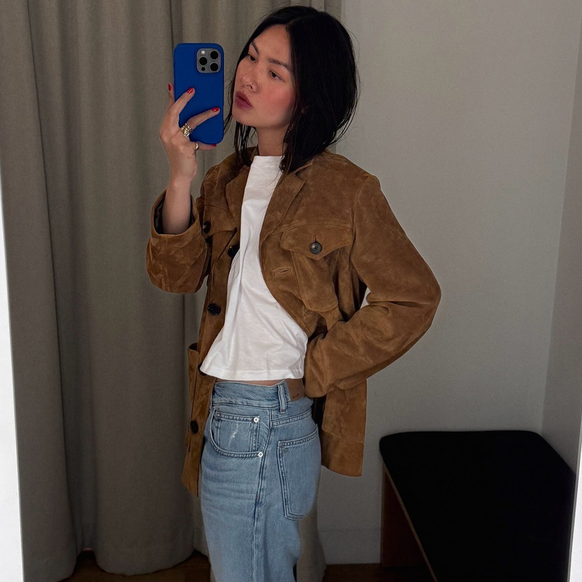 Mimi wears a suede jacket, white tee, and low-rise jeans.