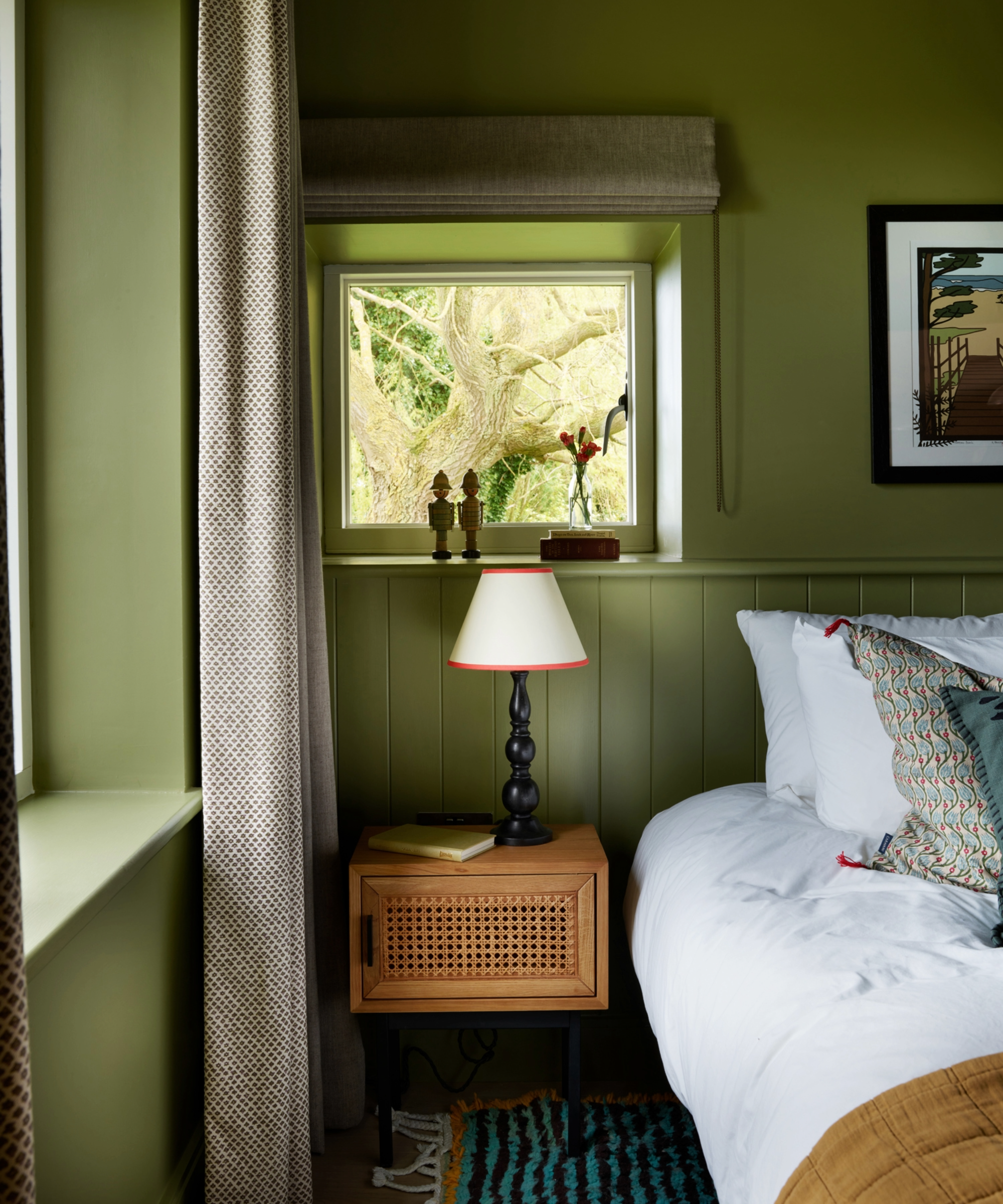Bedroom with green walls, green paneling, green window sill, and white bedding