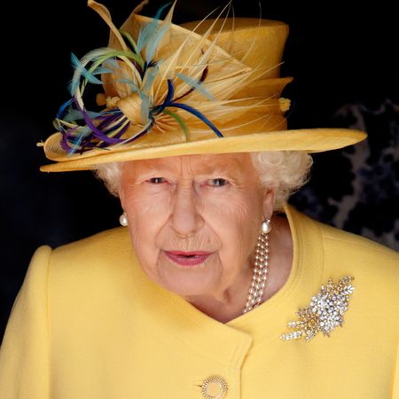 Queen Elizabeth wears a bright yellow coat and a matching hat with purple and blue feathers attached