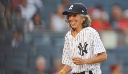 70-year-old honorary bat girl Gwen Goldman reacts after delivering baseballs to home plate umpire Scott Barry #87 during the first inning against the Los Angeles Angels at Yankee Stadium on June 28, 2021 in the Bronx borough of New York City.